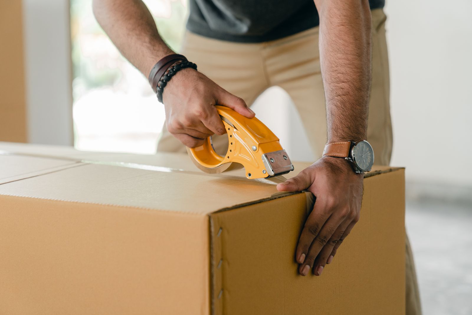 A cardboard box being sealed with packing tape